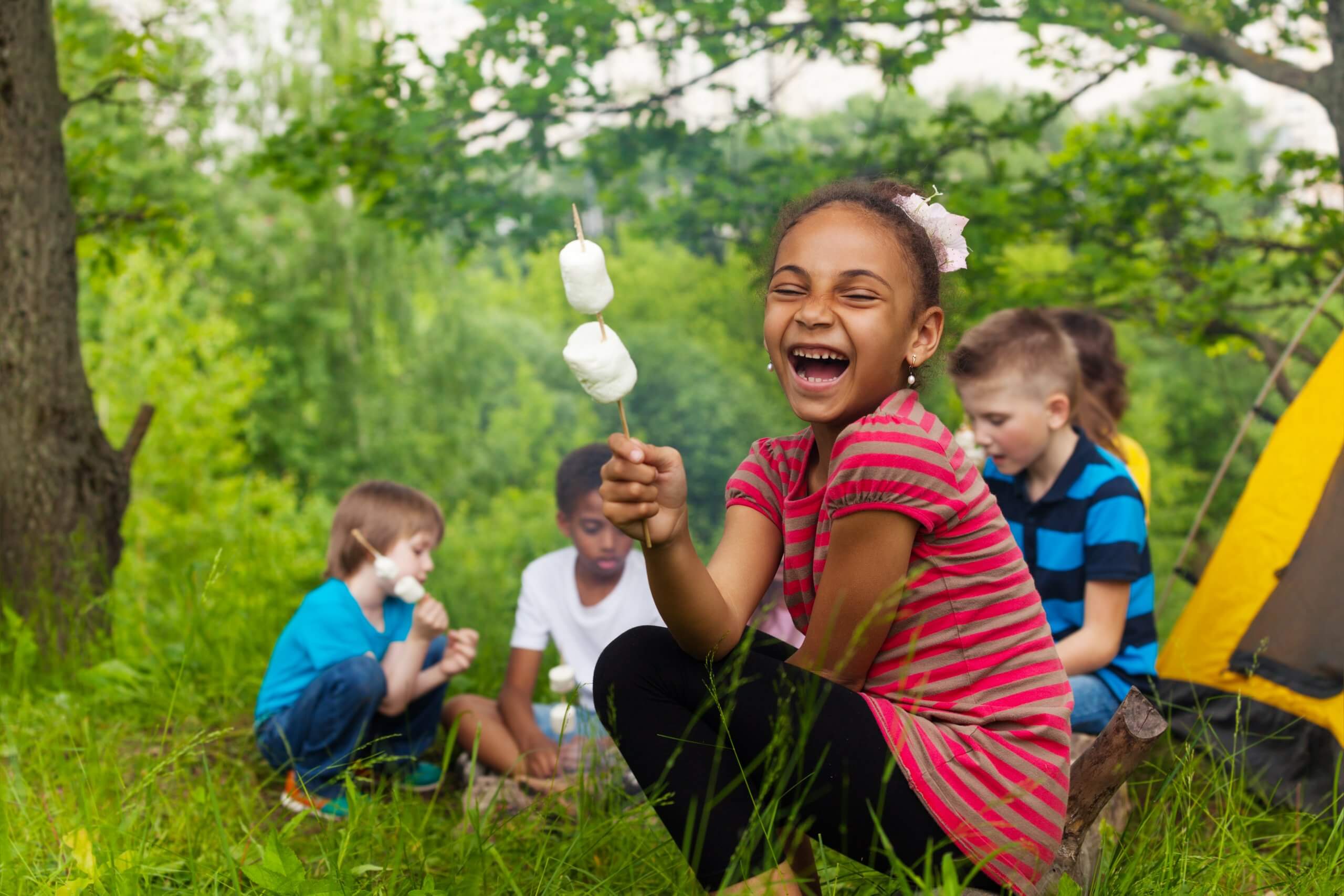 Laughing African girl holds stick with smores